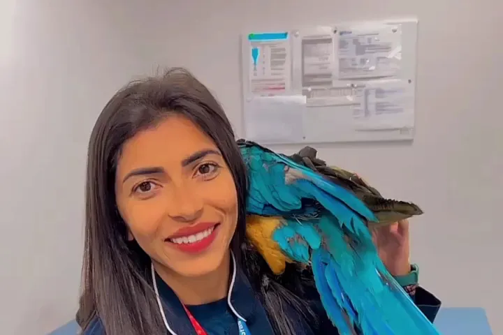 Veterinária do Grupo Santa Vida com uma arara no ombro